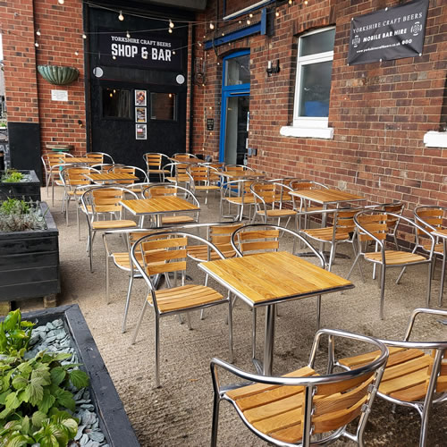 Beer garden with tables, benches, flower beds and lights