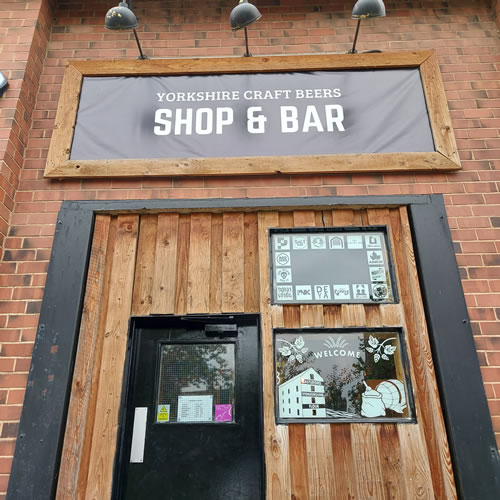 Front view of craft beer shop with door, window and sign