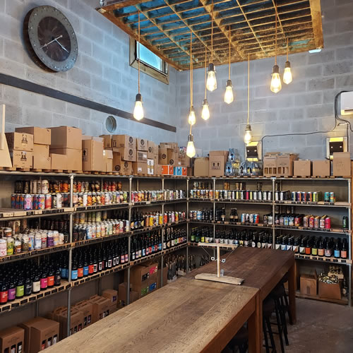 Shop and bar interior showing craft beers on shelves and bar seating area